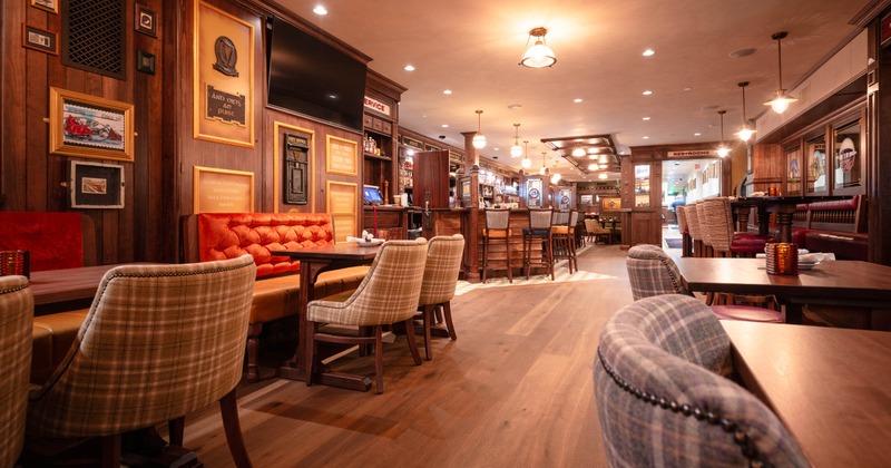 Interior, seating area, two-seater banquette benches with tables, bar area in  the back