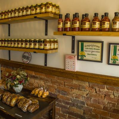 Interior with wooden shelves holding bottled goods and a counter with pastries.