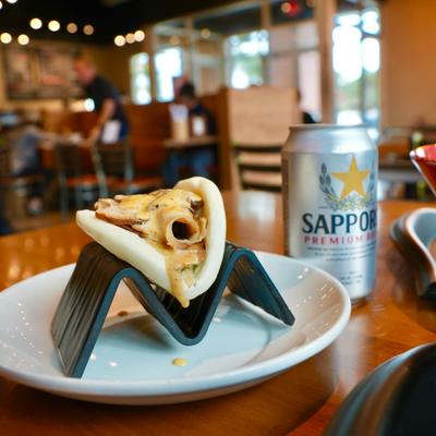 Pork Bao Bun served on a table with a caned drink.