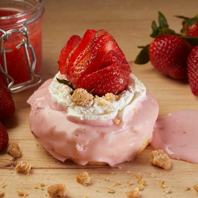 Strawberry shortcake donut topped with strawberry glaze, whipped cream, and strawberries.