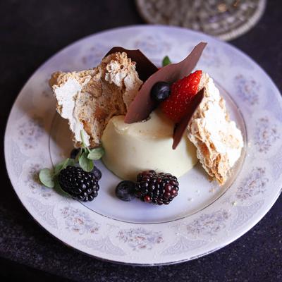 Lemon vanilla panna cotta with roasted cashew meringue, mixed berries, and house jam.