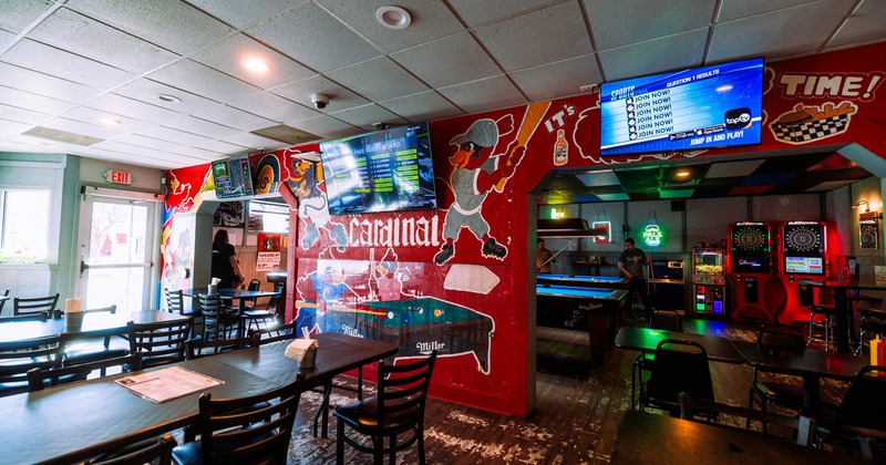 Interior, seating area, tables with chairs, electronic darts and pool tables in the back