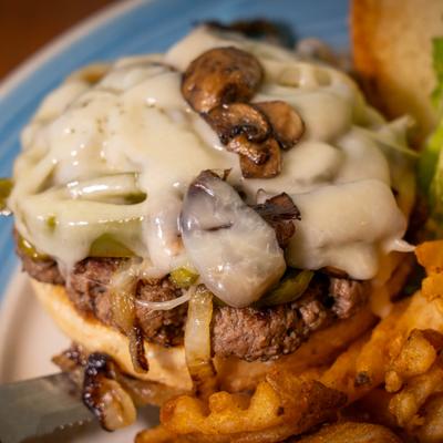 Gourmet Burger topped with mushrooms and Swiss cheese, close-up.