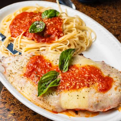 Chicken parmigiana served with spaghetti and tomato sauce.
