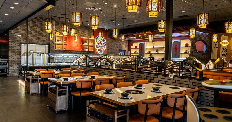 tables withInterior with orange chairs, decorative lanterns, and an open kitchen area in the background