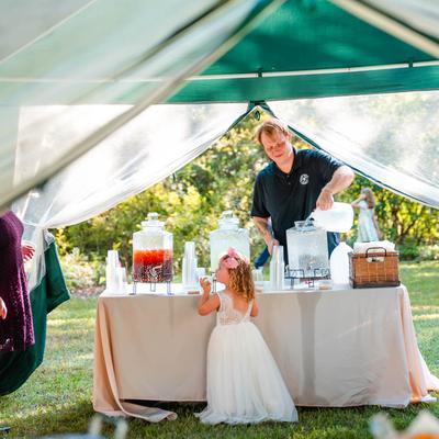 Outdoors wedding party, an employee serving refreshing beverages at a beverage station.
