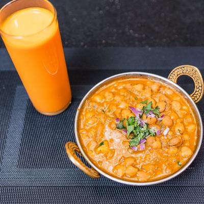 Chickpea curry served alongside a glass of mango lassi.