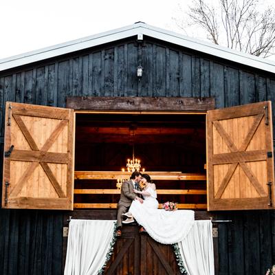 Wedding couple embracing on a barn balcony.
