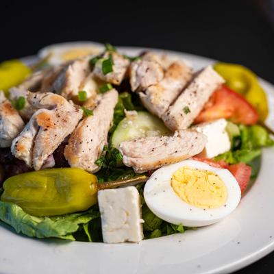 Mediterranean salad with grilled chicken, a hard-boiled egg, and fresh vegetables.