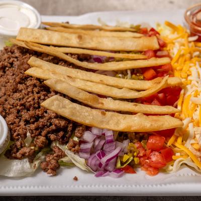 Taco salad with ground beef, tomatoes, cheese, onions, and tortilla strips.