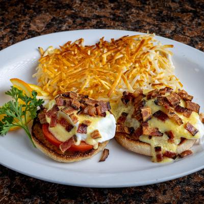Eggs Blackstone topped with hollandaise sauce and bacon, served with hash browns.