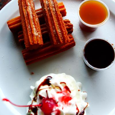 Churros served with dipping sauces and whipped cream.