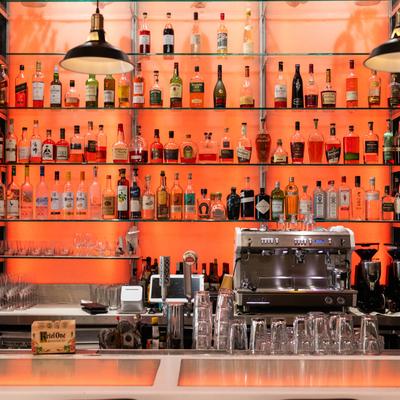 Bar shelving unit filled with various liquor bottles and a espresso machine behind the counter.