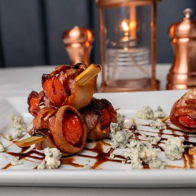 Shrimp, smoked bacon, blue cheese crumbles, balsamic reduction on a platter.