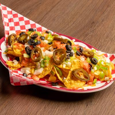 Nachos topped with pickled jalapenos, tomatoes, onions, olives, and peppers.