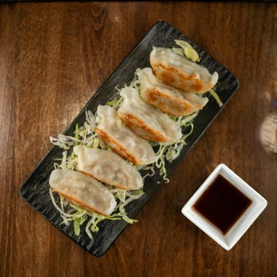 Gyoza dumplings served over shreded cabage with a dipping sauce on the side.