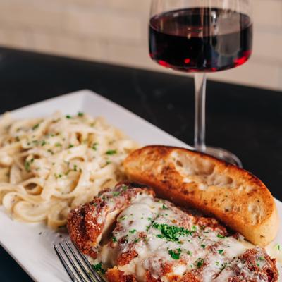 Chicken Parmesan with pasta, crostini, and a glass of red wine.