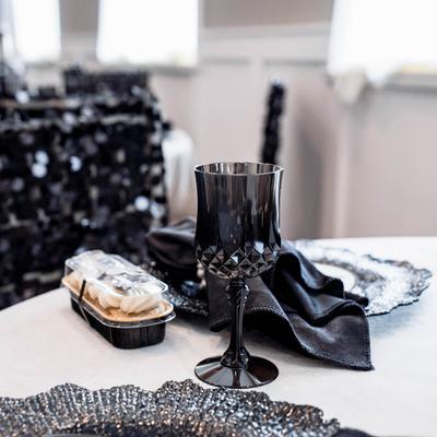 Black glass on a table, black napkin, food in plastic containers.