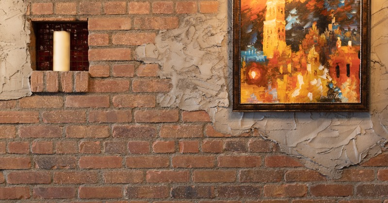 Interior, set table for two by a brick wall decorated with a painting
