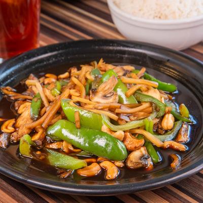 Stir-fried vegetables with cashews in dark sauce on a black plate.