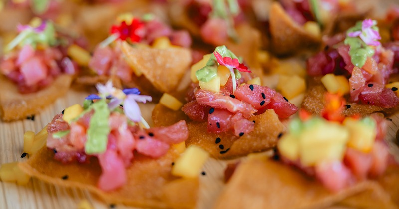 Tuna tostadas featuring raw diced tuna topped with avocado and edible flowers