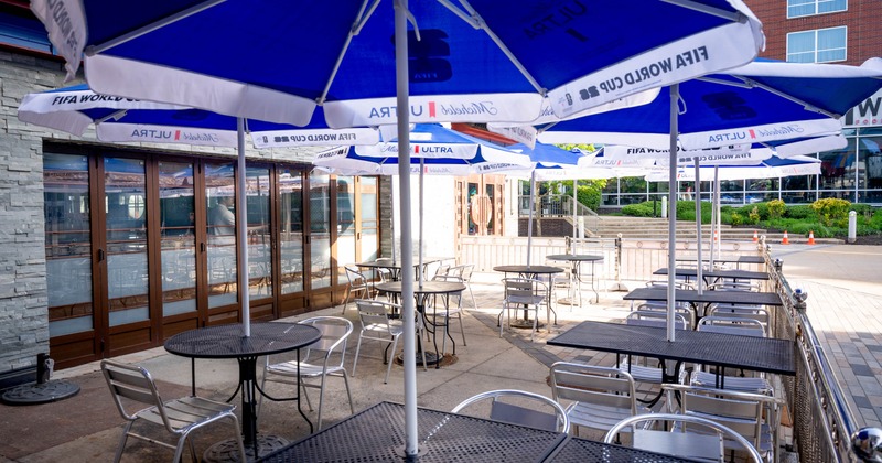 Outdoor patio with tables, chairs, and blue and white umbrellas