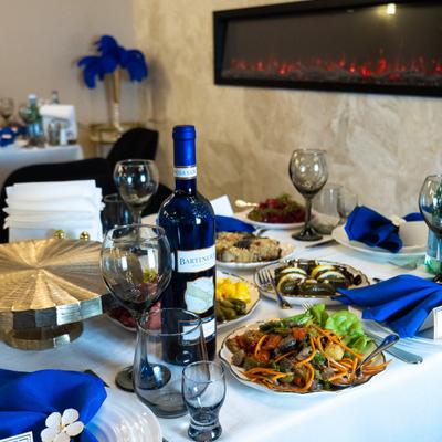 Elegant dining setting with white tablecloth, blue napkins, and a variety of dishes and wine.