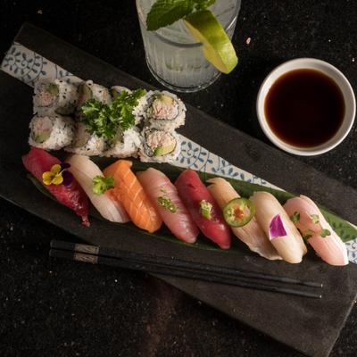 House sushi dinner with dipping sauce and a drink.