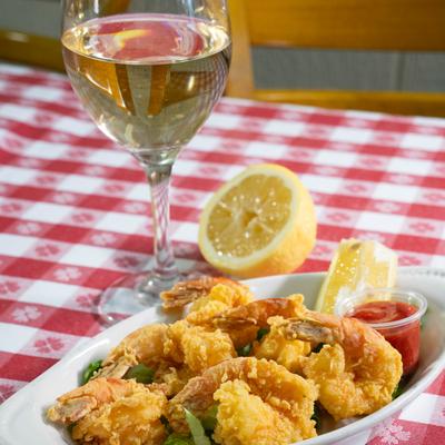 Crispy fried shrimp with lemon wedges and cocktail sauce, served with white wine.