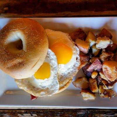 Two eggs on a bagel and side potatoes, top view