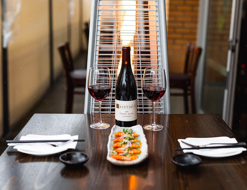 Two glasses of wine, bottle and sushi, served