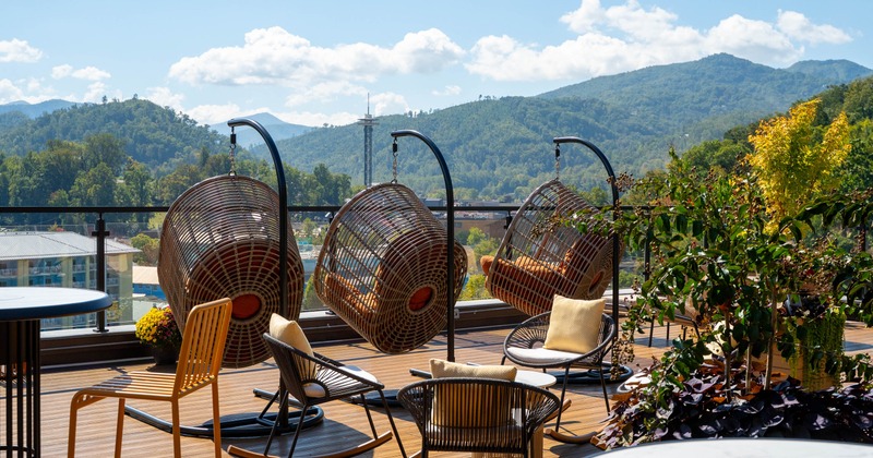 Rooftop patio with wicker hanging chairs and a scenic view