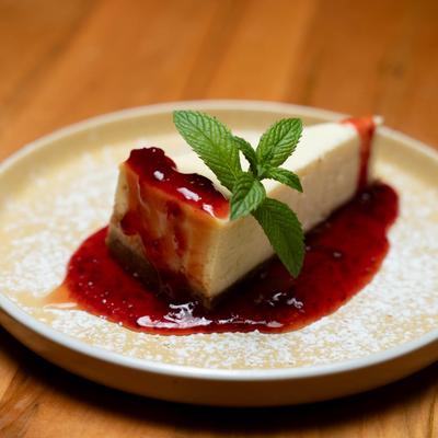 A slice of cheesecake with strawberry sauce.