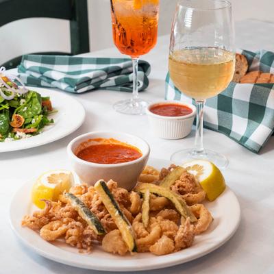 Fried calamari and fried zucchini accompanied by a salad, drinks, and bread.