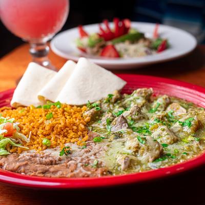 Sliced skirt steak in green salsa, with rice, beans, and tortillas.