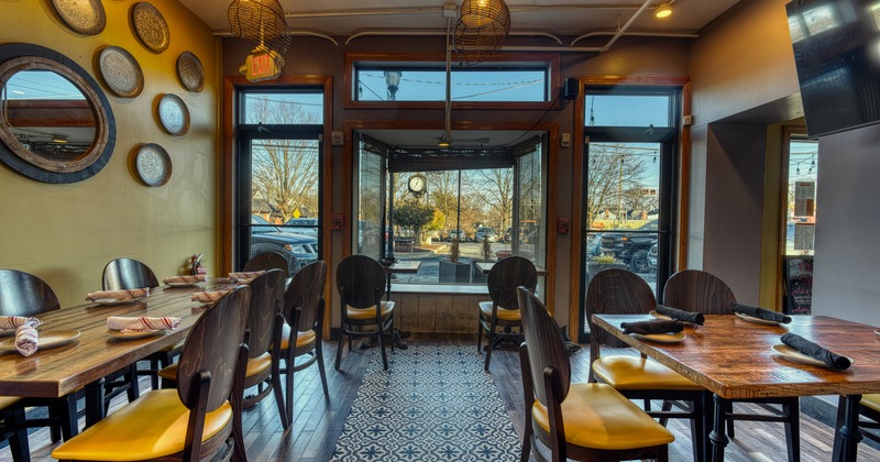 Interior, dining area with wooden tables and chairs, art and mirror on the wall