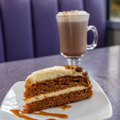 Carrot cake served with a cup of hot chocolate.