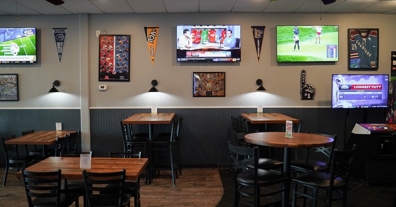 Diner area, tables, chairs, screens on a  wall above