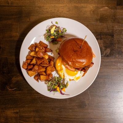 Egg and bacon burger served with home fries, top view.
