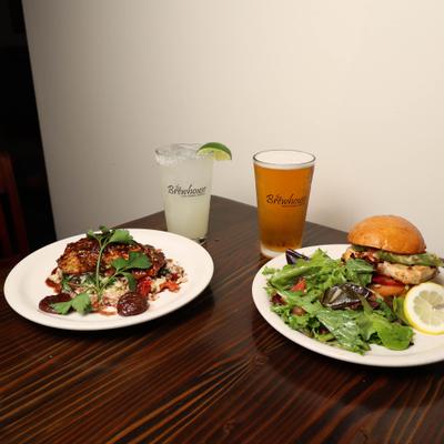 plate of Grilled salmon and plate of Grilled Chicken sandwich with house salad , Beer and margarita.