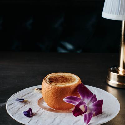 Grapefruit cocktail in hollowed fruit with orchid petals.