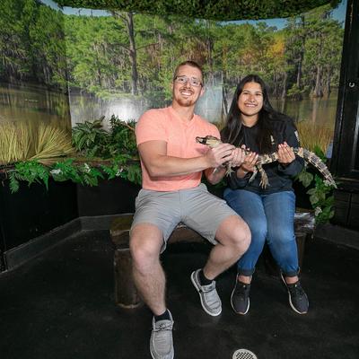 A portrait shot of a  couple holding a juvenile alligator.