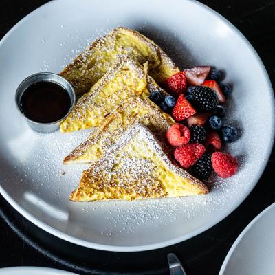 Frenc toast dusted with powdered sugar, served with syrup and fresh berries.