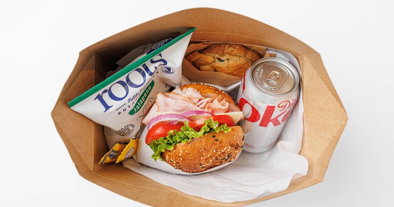 Bagel sandwich meal in a takeout box with chips and soft drink