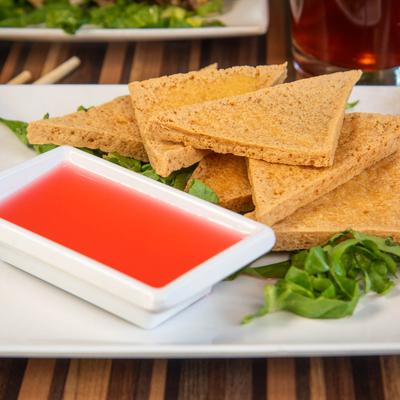 Fried tofu triangles served with bright red dipping sauce.