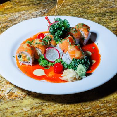 Dynamite roll on a white plate with sauce and vegetable garnish.