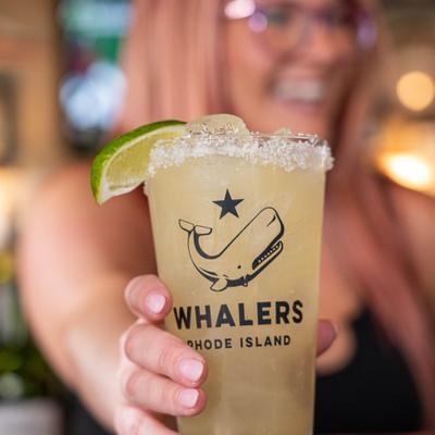 Staff member holding Margarita cocktail in pint glass.