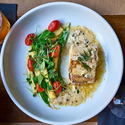 Wahoo fish filet served with pan seared vegetables.