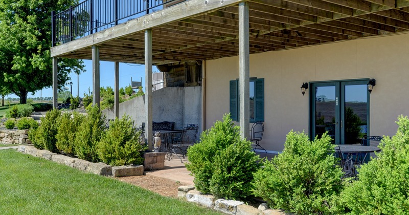 Serene seating area under terrace with shrub fence line and  green lawn