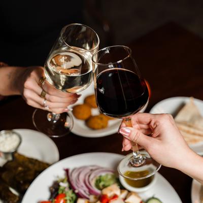 People clinking wine glasses over the table.